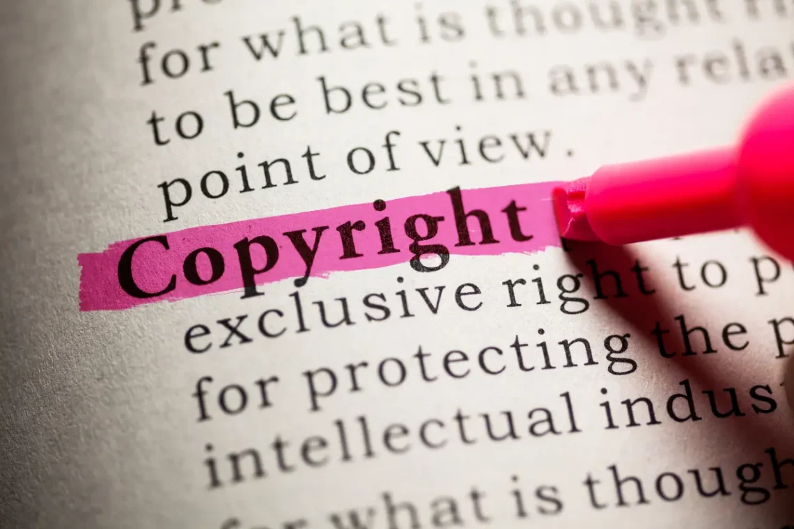 Ordet "Copyright" er fremhævet med en pink overstregning i en ordbogstekst. Det relaterer sig til ophavsret og beskyttelse af kreativt indhold.