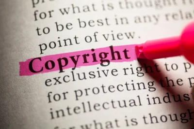 Ordet "Copyright" er fremhævet med en pink overstregning i en ordbogstekst. Det relaterer sig til ophavsret og beskyttelse af kreativt indhold.